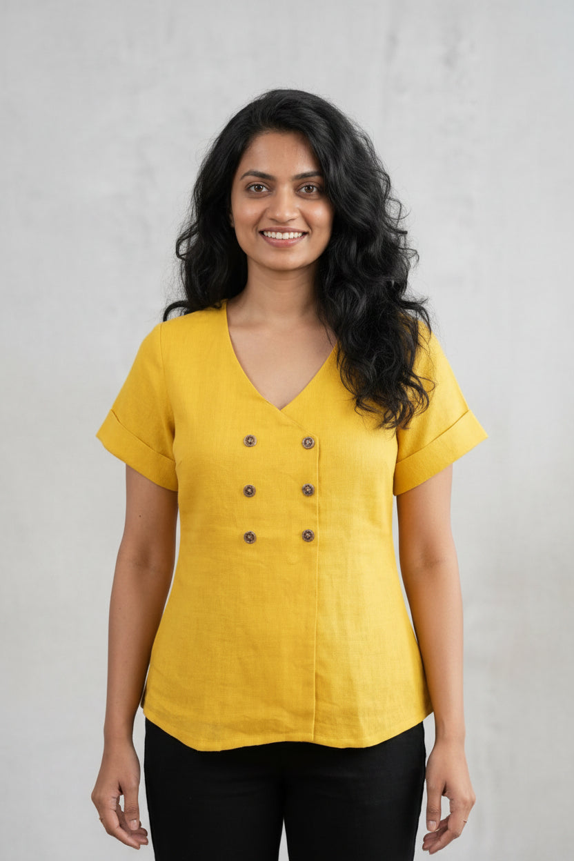 Woman wearing a yellow top with buttons against a plain background